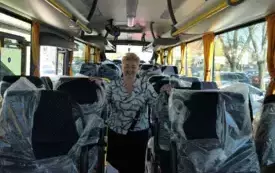 Wnętrze autobusu, po obu stronach ofoliowane fotele pomiędzy fotelami stoi zastępca burmistrza Łochowa Małgorzata Łotarska