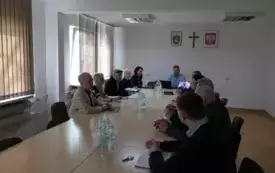 Grupa os&oacute;b siedzi przy stole na sali konferencyjnej w Urzędzie Miejskim w Łochowie